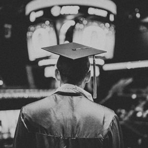 man wearing graduation gown approaching the stage