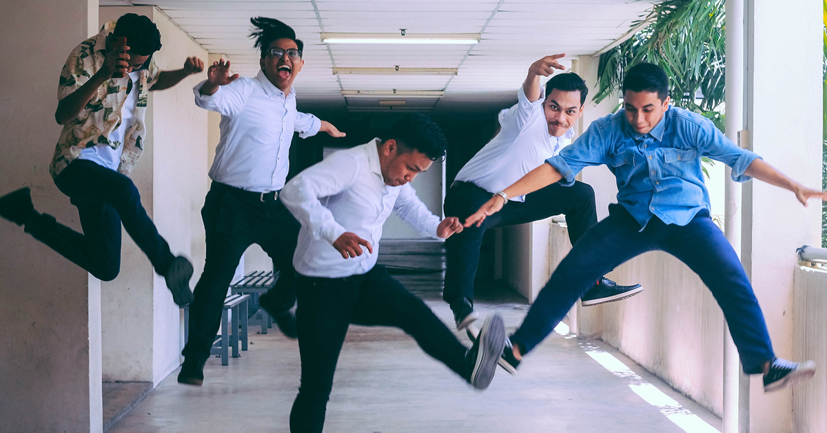 Five international students jumping in a hallway